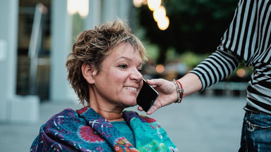 Einer Frau wird ihr Handy ans Ohr gehalten