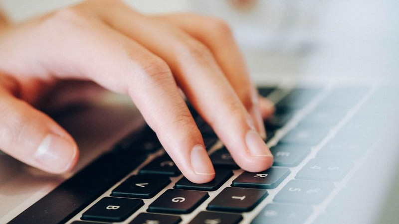 Online-Veranstaltung. Die Hand tippt auf Computertastatur.