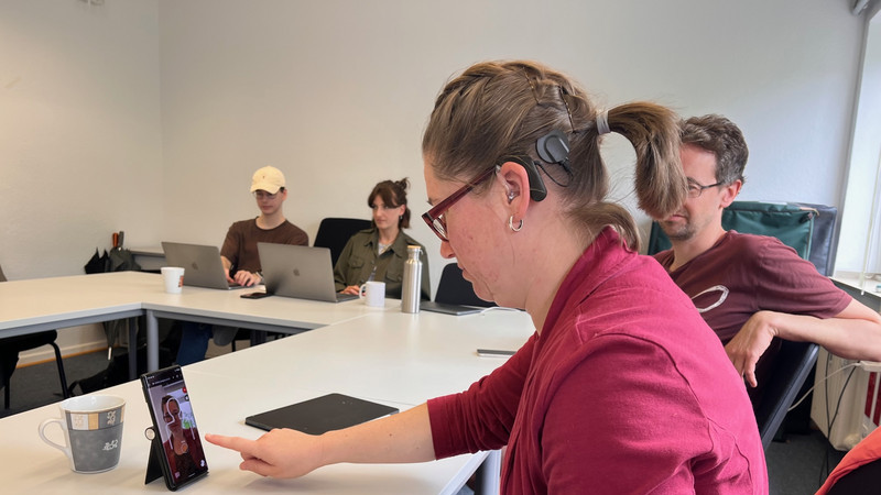 Frau Wegerhoff tippt auf dem Smartphone Frau Wegerhoff tippt mit dem Finger auf dem Smartphone am Tisch.