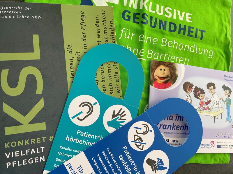 Praxishandbuch, Türanhänger, Tasche "Inklusive Gesundheit und Buch "Nina im Krankenhaus" sind dargestellt.