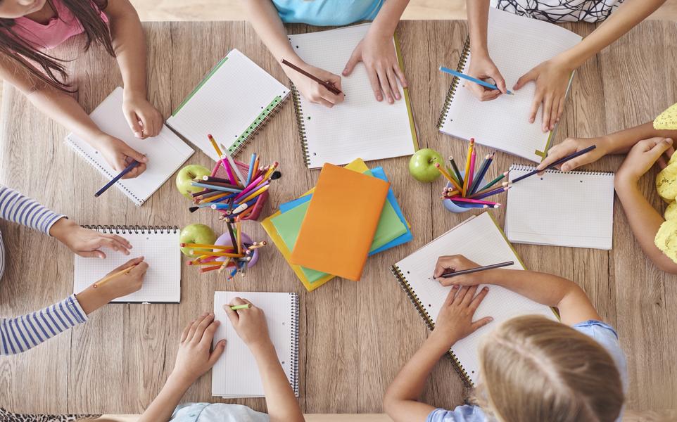 Die Kinder sitzen am Tisch und schrieben die Aufgabe.